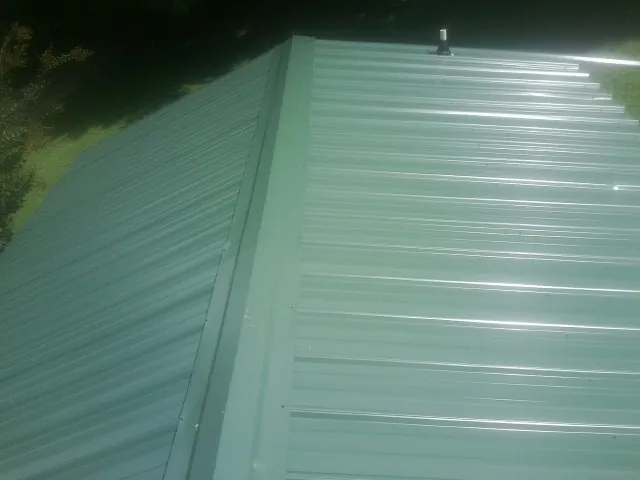 New green metal panels meeting at the ridge of a roof — Flat Roof Repair work by our crew in River Grove