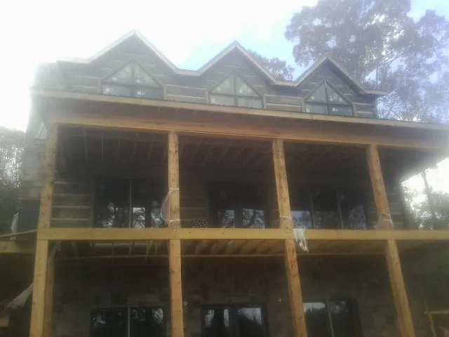 Dormers and porch framing on a large log home under construction — Roof Coating work by our crew in River Grove