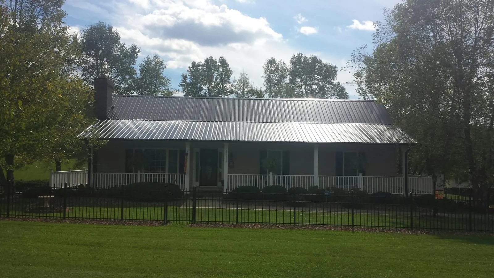 Gray metal roof on a brick ranch with a full width front porch — Gutter Guard Installation work by our crew in River Grove