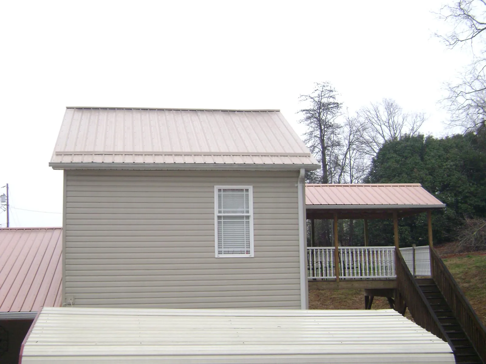 Tan metal roofs on a two story addition and attached porch, from a Roof Replacement job in River Grove