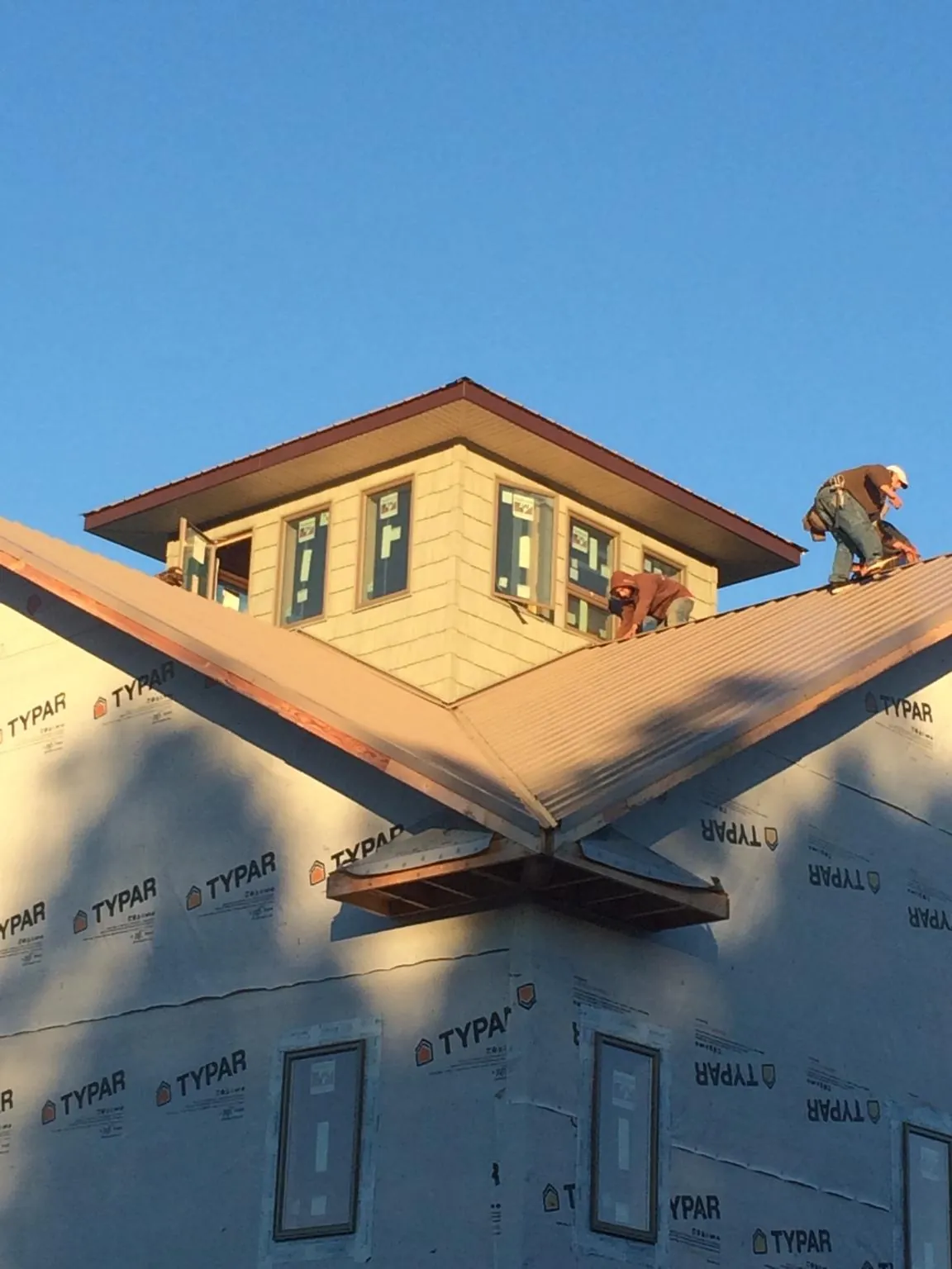 Roofers working around a rooftop cupola on a new metal roof at sunset — Roof Waterproofing in River Grove by Roofing Brothers